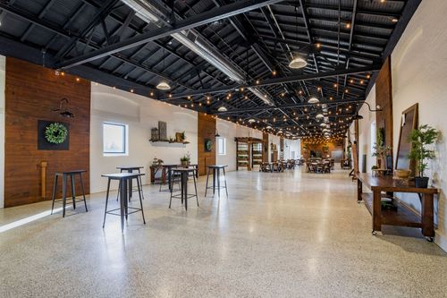 Open event space with high-top cocktail tables, string lights, and wood accent walls