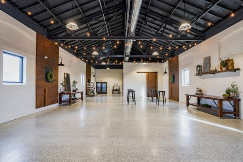 Open event hall with string lights, wood accent walls, and mixed lounge and cocktail seating