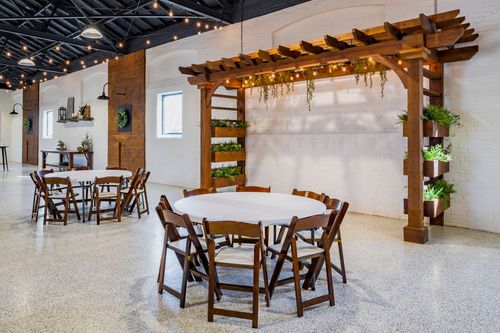 Wood pergola arbor with vertical planters and a round table set with linens nearby