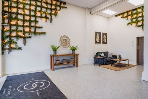 Lobby corner with greenery wall installations, a wood console table, and a leather sofa set