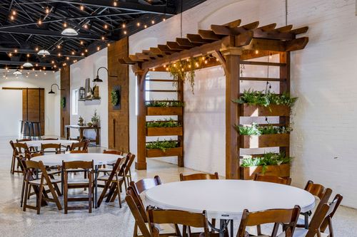 Display shelf with decor beside round tables set with white linens under string lights