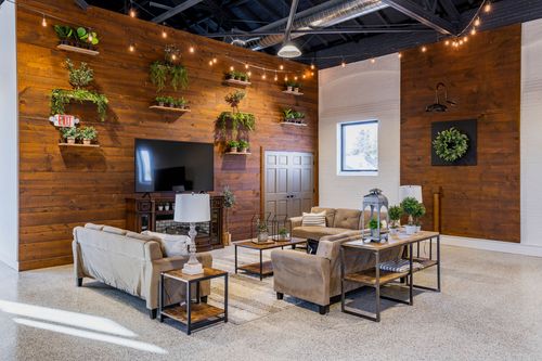 Lounge area with a reclaimed wood accent wall, hanging planters, a mounted TV, and sectional seating