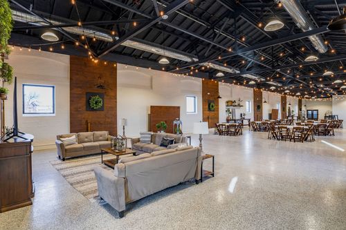 Lounge seating area with sofas, a rug, and a wood accent wall wreath near dining tables