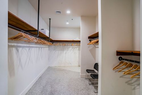Dressing room interior with wood shelving, clothing rods, and an exposed brick accent wall