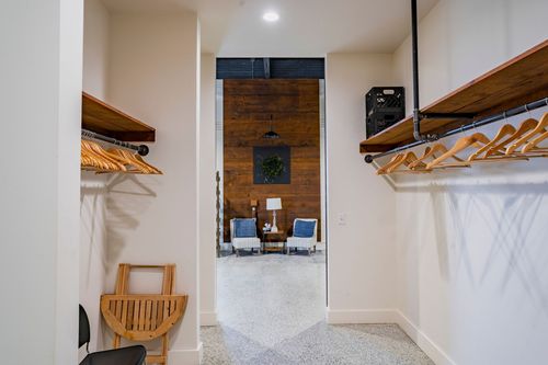 Closet hallway with wood shelving and hangers opening into a wood-paneled lounge area