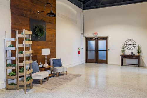Seating nook with a wood ladder planter shelf, wreath, upholstered chairs, and a wall clock