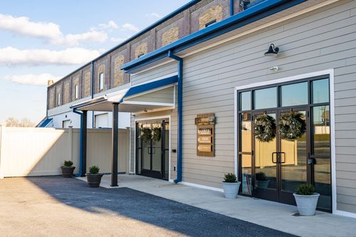Side view of a renovated mill building with awning entrance, tan siding, and a tenant directory sign