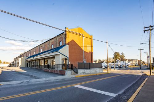 Street view of an orange brick mill tower with arched windows across from town houses