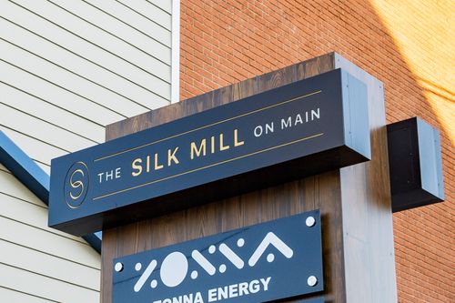 Close-up of The Silk Mill on Main sign mounted on brick above a business directory board