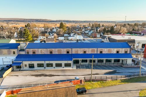 Aerial view of a mill building's blue metal roof and parking area at golden hour