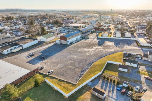 Aerial dusk view of a large graded lot beside a renovated mill building with a small town in the distance