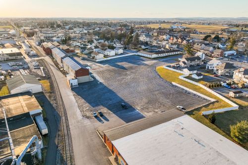 Aerial dusk view of a graded lot with curved landscaped border near homes and a church steeple
