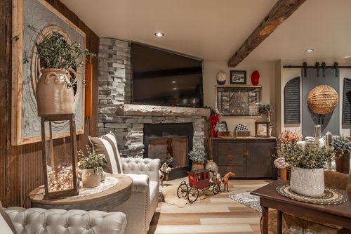 Living room with stacked-stone fireplace, mounted TV, wood cabinet and a vintage red toy wagon