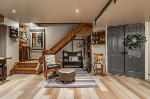 Basement entry with wood staircase, rocking chair, black bench and charcoal paneled doors