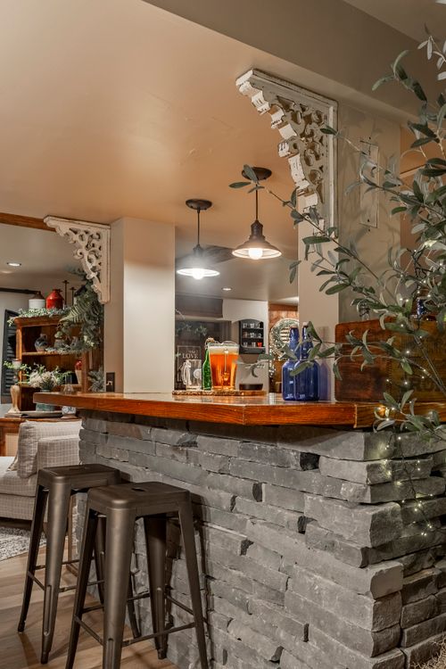 Close-up of a stone bar counter with vintage corbels, pendant lights and metal barstools