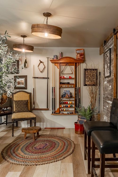 Basement game room with a pool cue rack, wainscoted walls, drum pendant lights and a braided rug