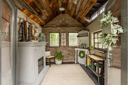 Converted studio with a wood plank vaulted ceiling, stone accent wall, and a white painted fireplace mantel