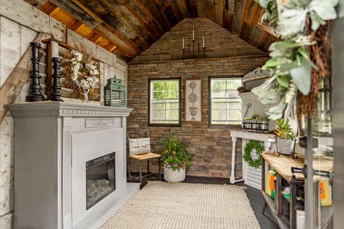 Close view of a white fireplace mantel styled with dried florals beneath a stone accent wall and wood ceiling
