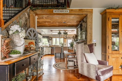 Open living and kitchen area with a wood staircase, stone accent wall, and an Antiques sign