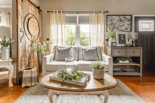 Living room with a weathered barn door, console table, cream sofa, and round coffee table