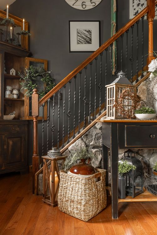Entryway staircase with a dark hutch, candle display, and woven basket on hardwood floors