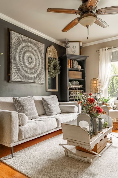 Living room with a dark accent wall, tapestry art, dark bookcase, and a cream sofa with fresh florals