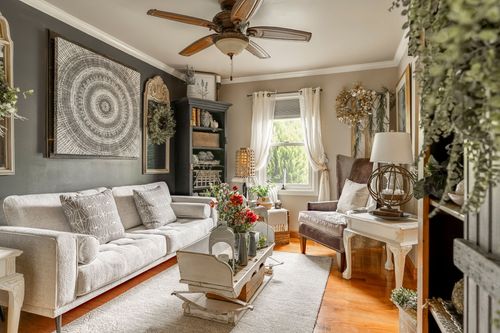 Living room with a gray sofa, dark bookcase, wreathed mirror, and round tapestry wall art