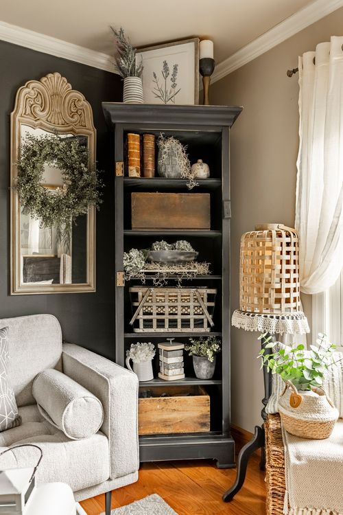 Corner vignette with a dark bookcase styled with books and crates beside a wreathed mirror