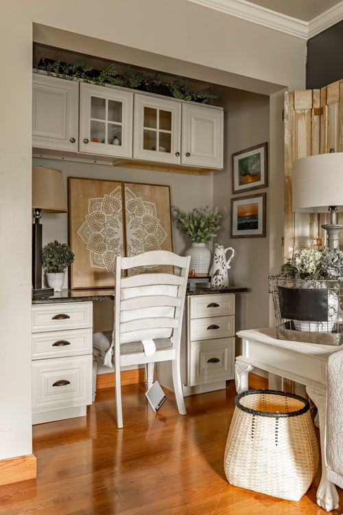 Home office nook with white cabinetry, a mandala wall art panel, built-in desk, and a wicker basket
