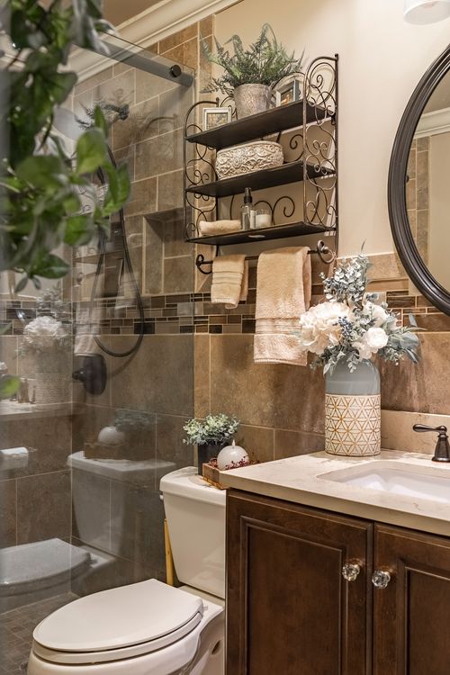 Bathroom vanity corner with an iron shelf, towels, round mirror, and floral decor