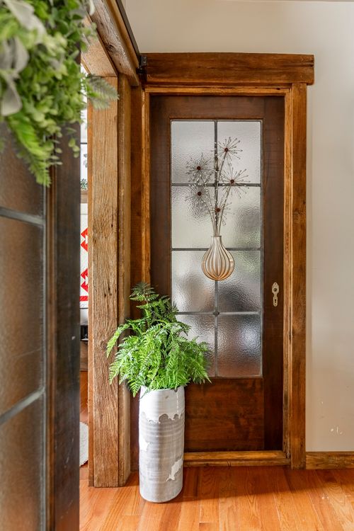 Entry with a wood-framed frosted glass door and a vase of dried flowers on hardwood floors