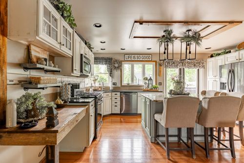Farmhouse kitchen with white cabinets, a sage green island, and upholstered barstools
