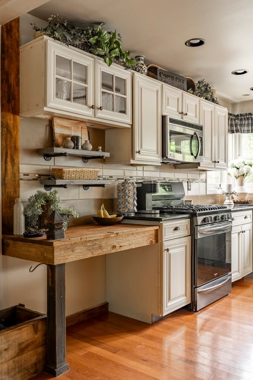 Kitchen with white cabinets, industrial pipe shelving, and a stainless range with hood