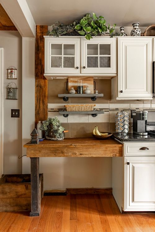 Kitchen detail with industrial pipe shelving styled with pottery and a reclaimed wood butcher block counter