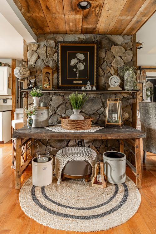 Dining nook with a stacked stone accent wall, wood beam ceiling, and a rustic console styled with crocks