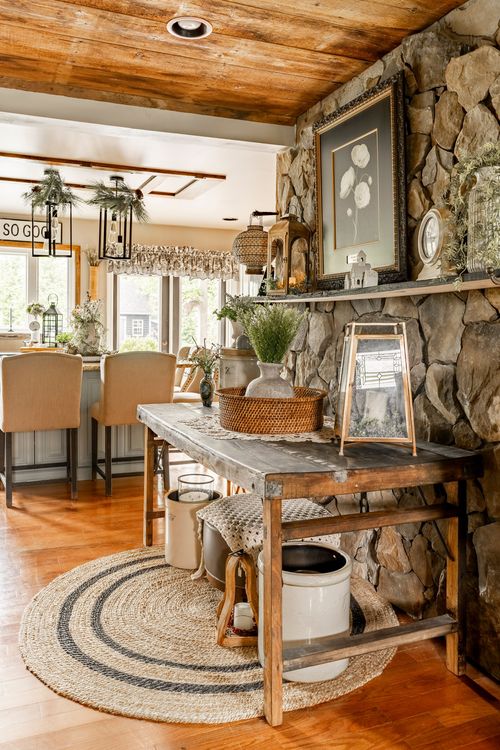 Rustic dining nook with a stone accent wall, wood beam ceiling, and a farm table styled with lanterns