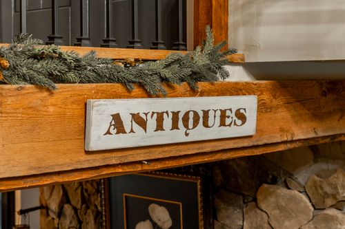 Close-up of an Antiques sign on a reclaimed wood beam with a pine garland