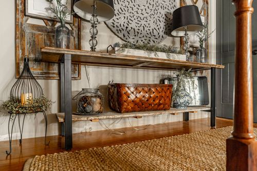 Entryway console table styled with lamps, tapestry art, and a woven basket on a jute rug