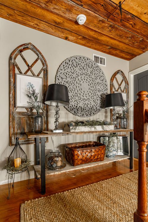 Hallway console with arched mirrors, black lamps, and a gray medallion wall art piece