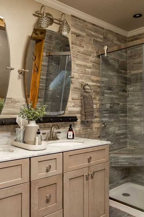 Bathroom vanity detail with an arched mirror, marble countertop, and tiled shower wall