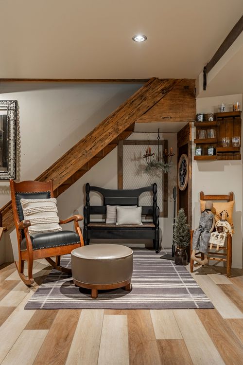 Reading nook under a staircase with rocking chair, black bench, round ottoman and reclaimed beams