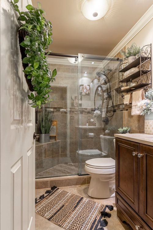 Bathroom with a glass-enclosed tile shower, dark wood vanity, and a trailing hanging plant