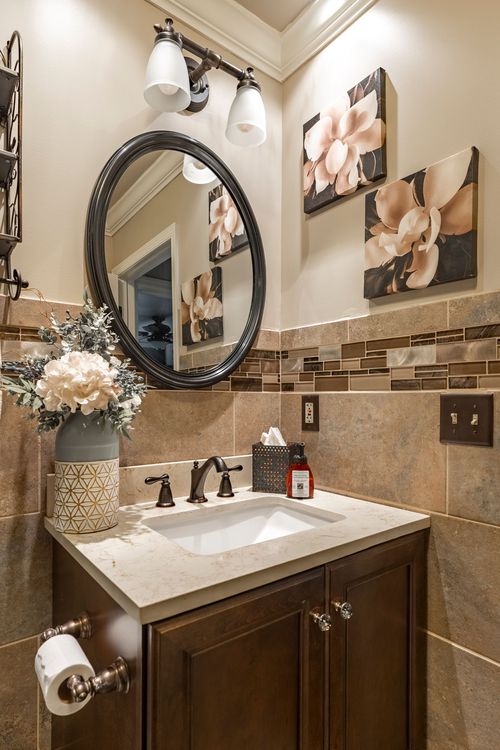 Powder room with a round mirror, floral wall art, and a quartz-topped dark wood vanity