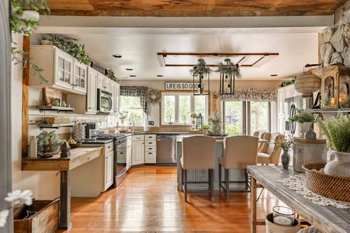 Farmhouse kitchen with white cabinetry, a wood beam ceiling accent, and an island with barstools