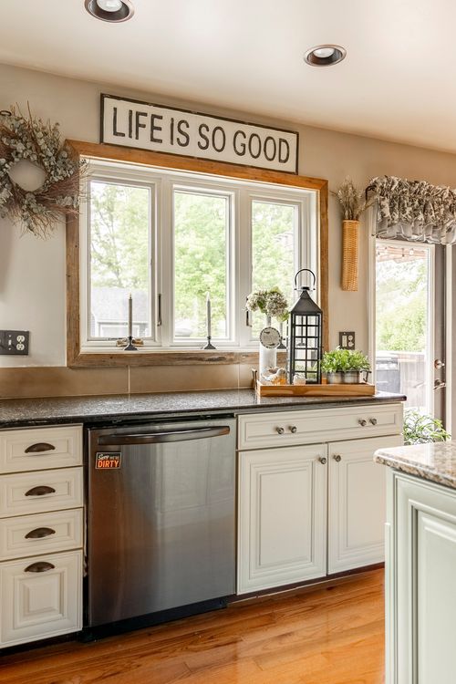 Kitchen window detail with a wood frame, dried wreath, and black countertops