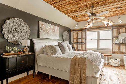 Primary bedroom with a dark accent wall, medallion art, white bed, and black nightstand