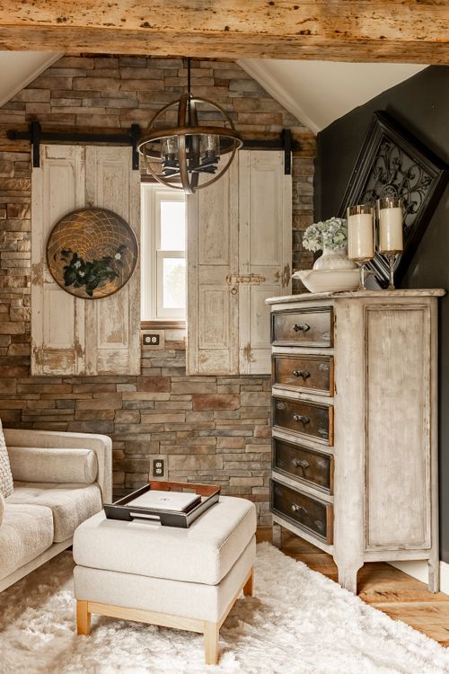Sitting nook with a stacked stone wall, reclaimed wood shutters, orb chandelier, and a distressed dresser