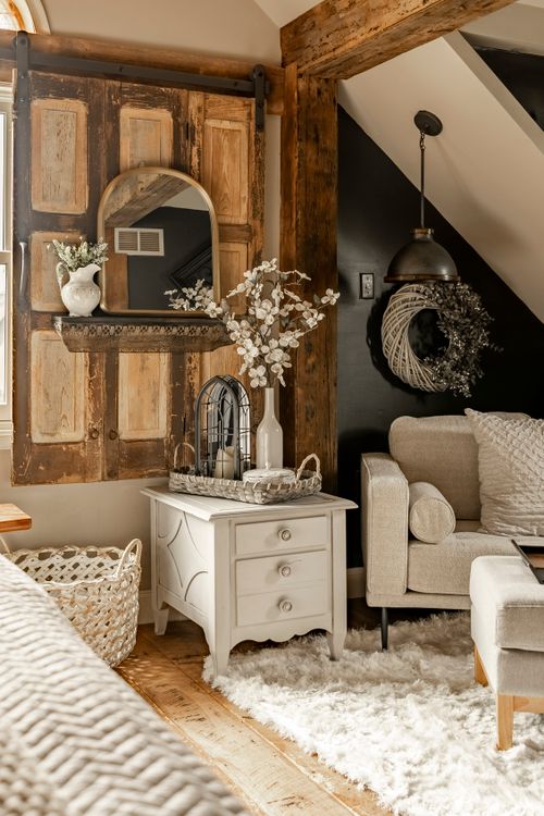 Sitting area with a reclaimed wood barn door shelf, white nightstand, and armchair on a shag rug