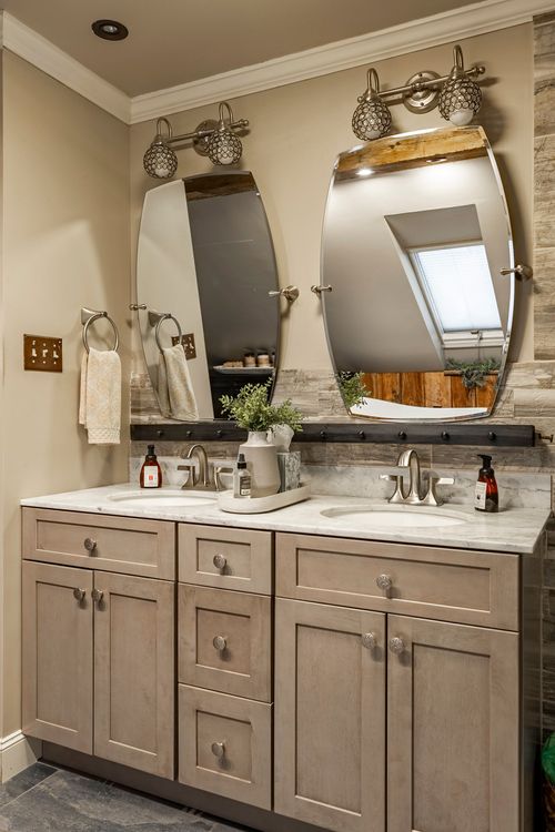 Double vanity with oval mirrors, sconce lighting, and marble countertops in a primary bathroom