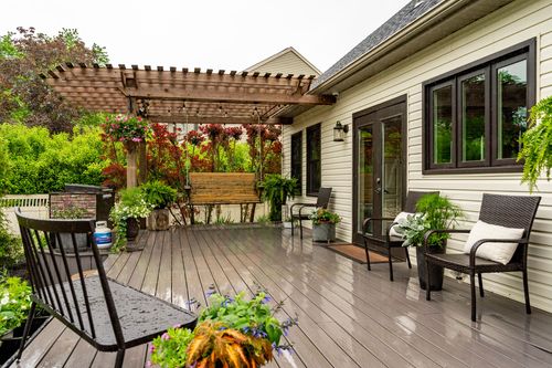 Covered back deck with a wood pergola, hanging flower baskets, wicker seating, and French doors